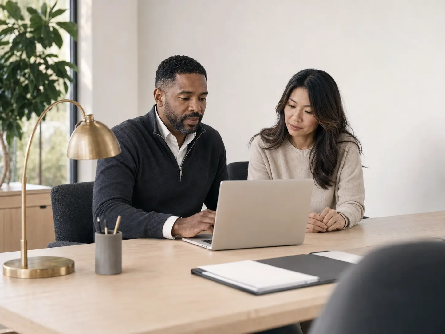 A loan professional and a client working side by side at a laptop